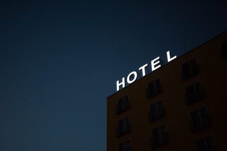 low-angle photo of global hotel card eligible Hotel lighted signage on top of brown building during nighttime